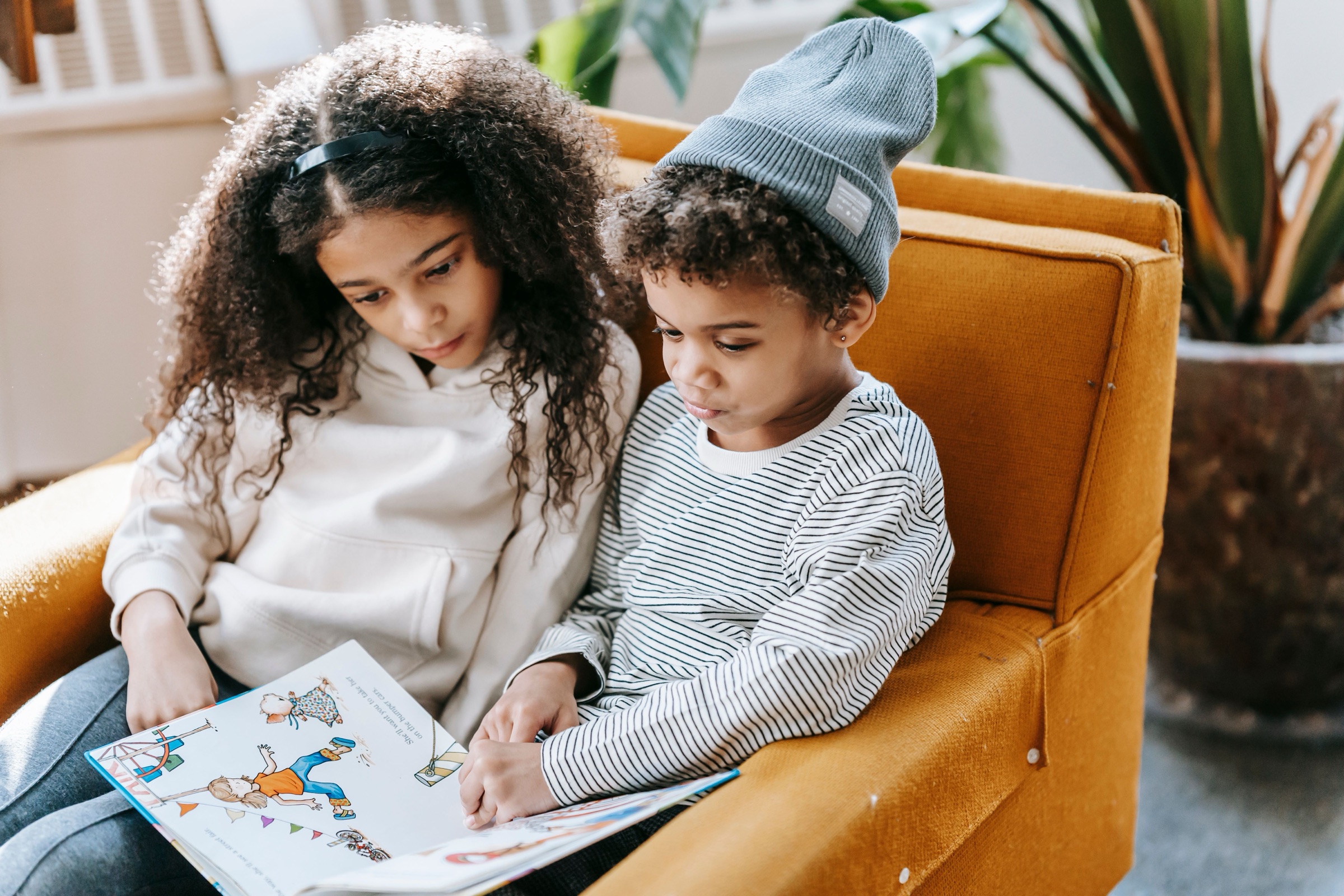 Two Black children reading a picture book together