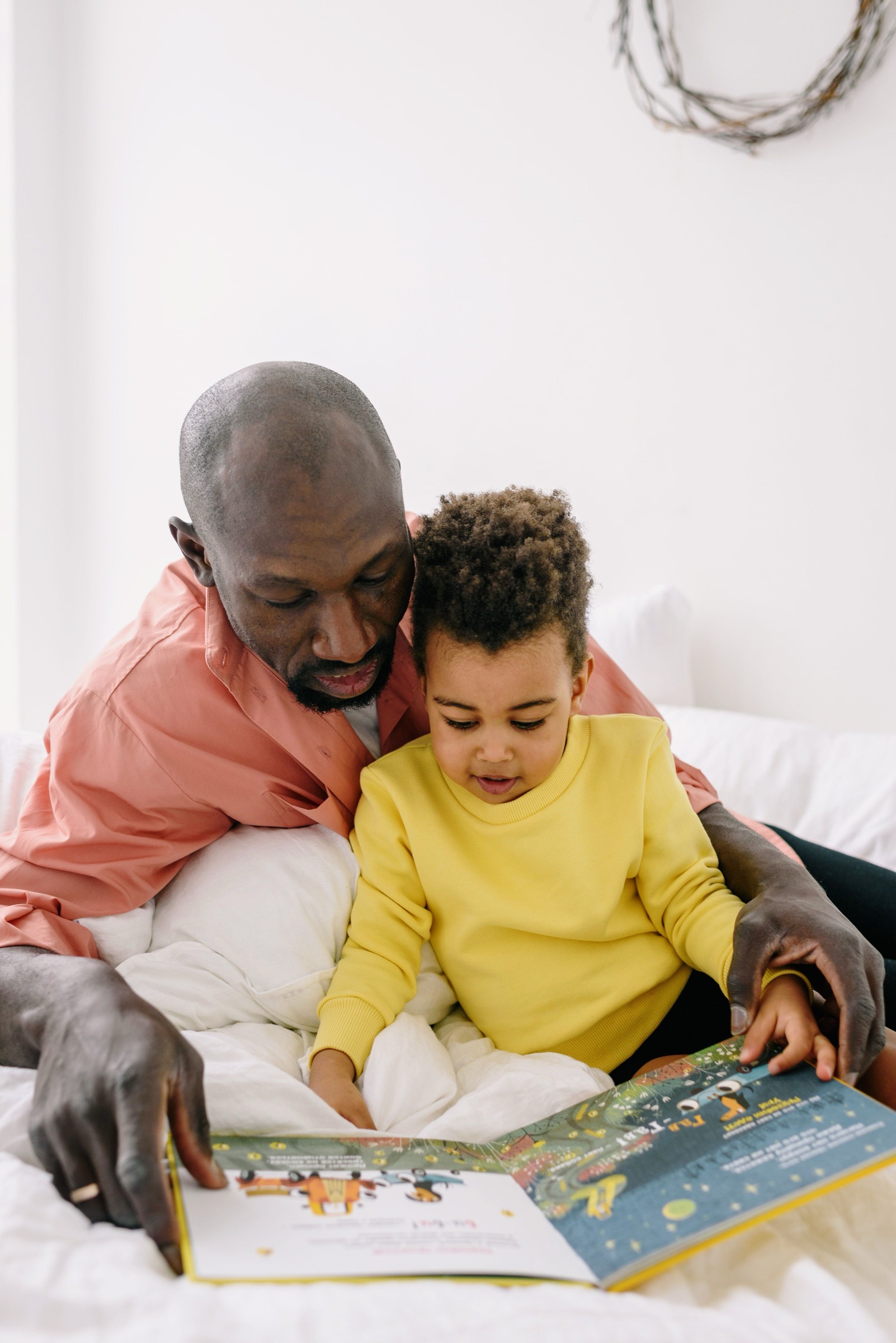 A Black father and child sharing a book