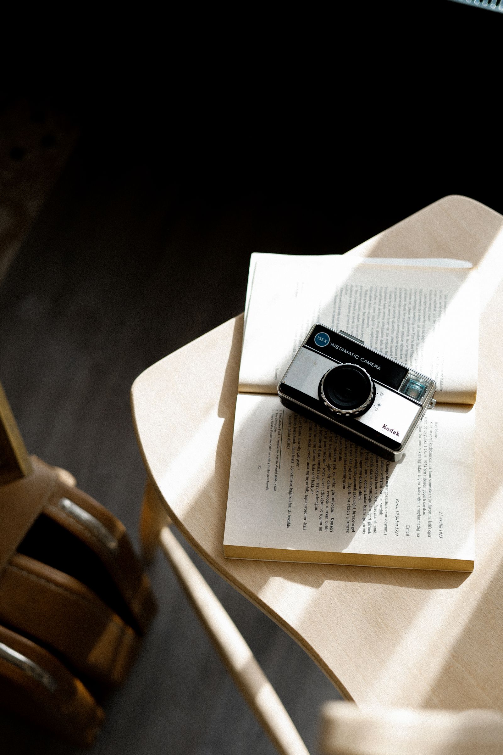 A vintage camera resting beside an open book